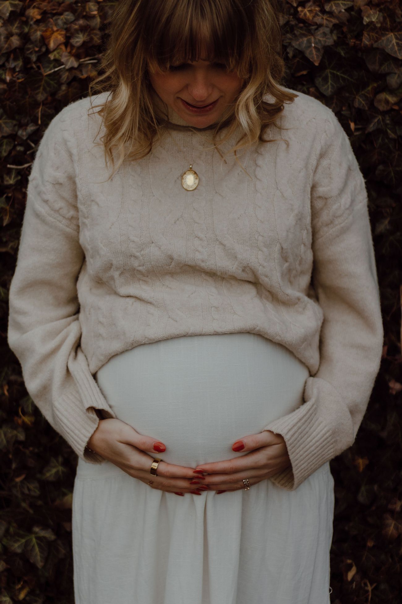 Cream sweater, hands cradling her belly