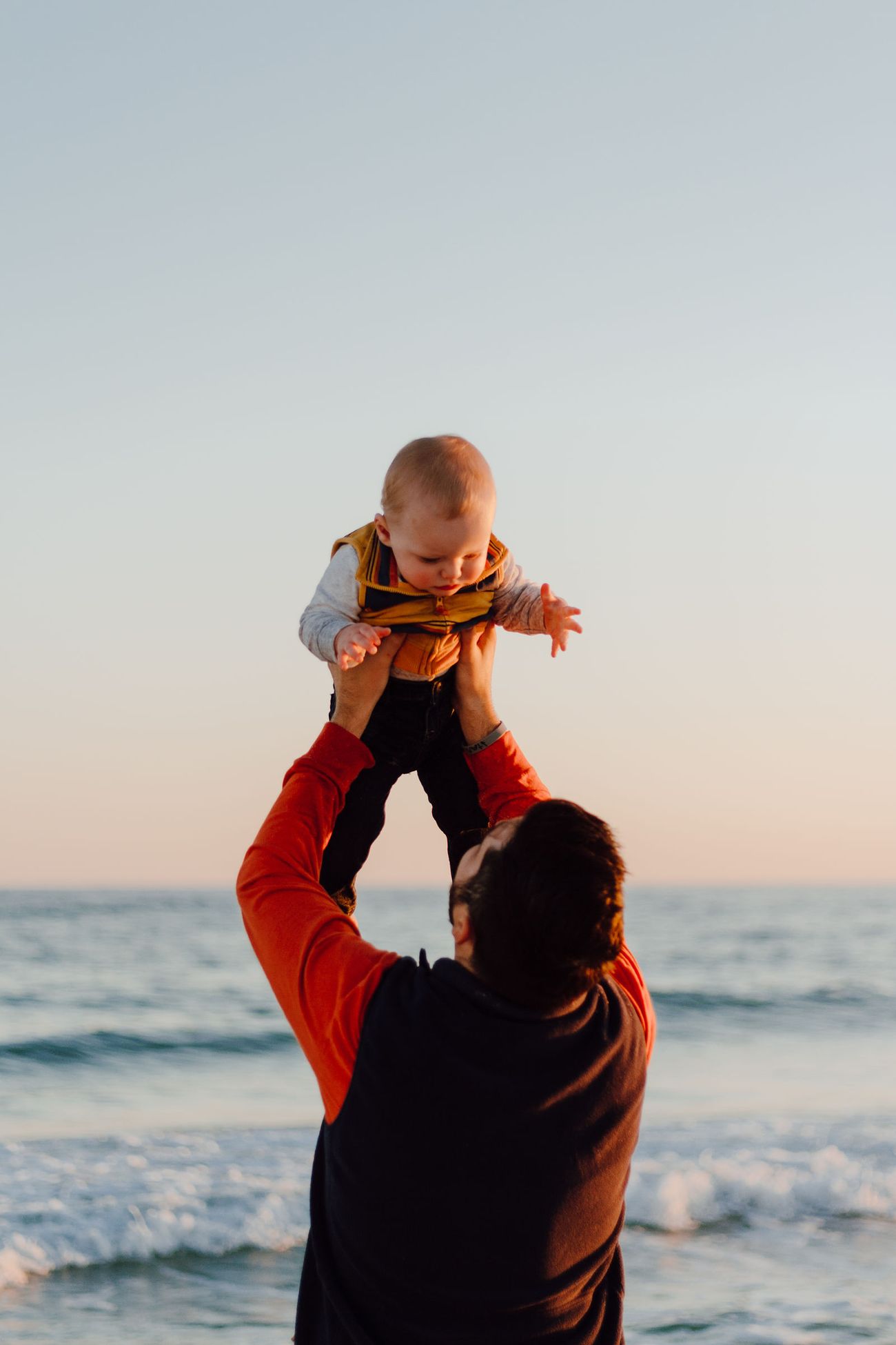 Dad lifting his son toward the sky