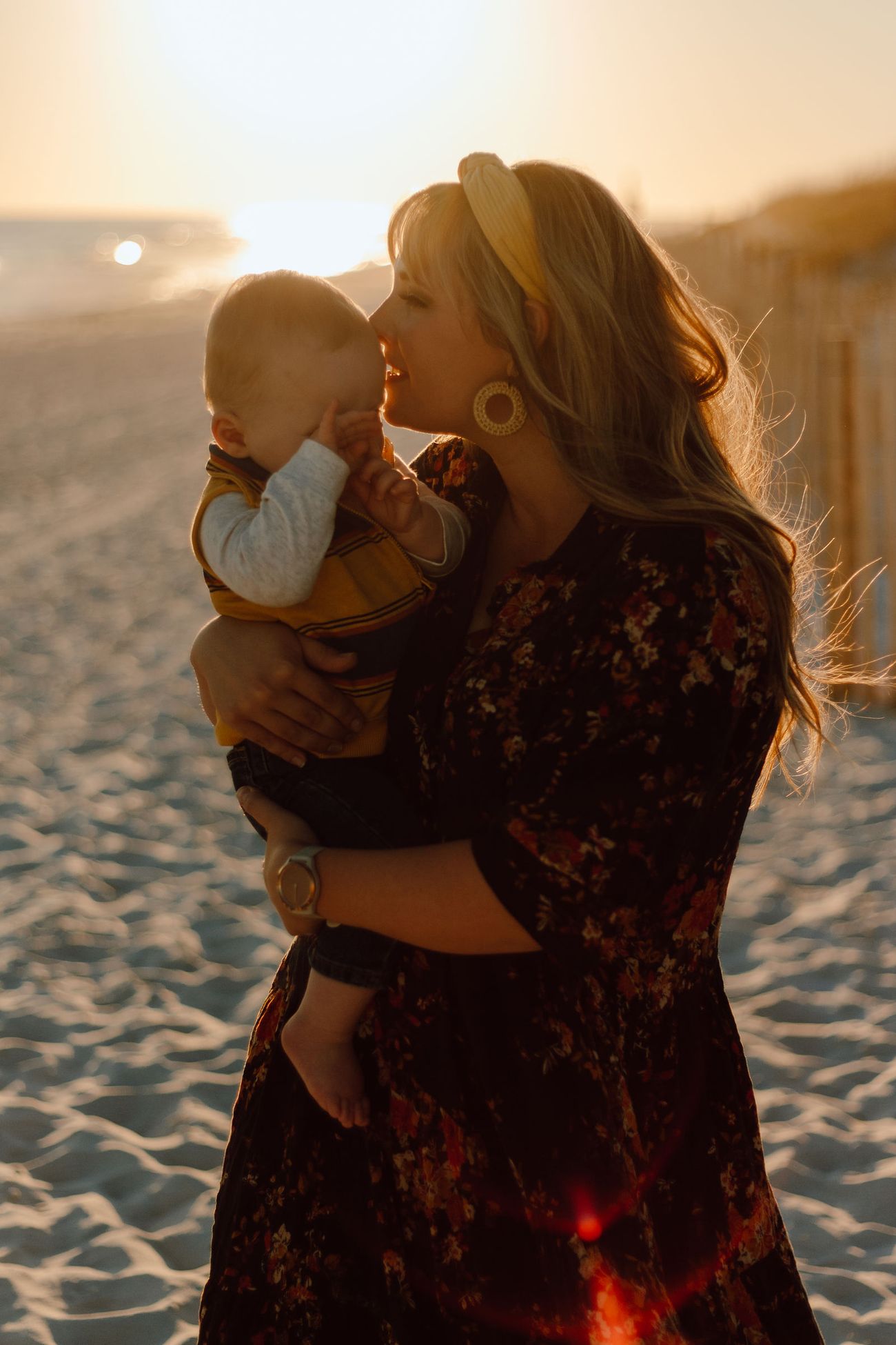 Mom holding her baby up against the setting sun